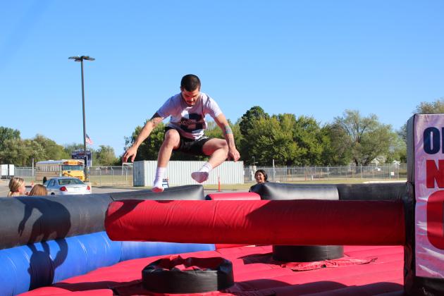 Shawnee 2019 graduate and former wrestler Edward Chotkey jumps over a spinning bar of the Oklahoma National Guard obstacle course during the Shawnee Wrestling Carnival on Oct. 13 at Shawnee High School. The event has been put on by the wrestling department for four years, and Coach Andrew McCune said they just do it for the kids in the community. This year, they joined forces with First United Bank to add their annual "tailgate party" and grilled hamburgers.
