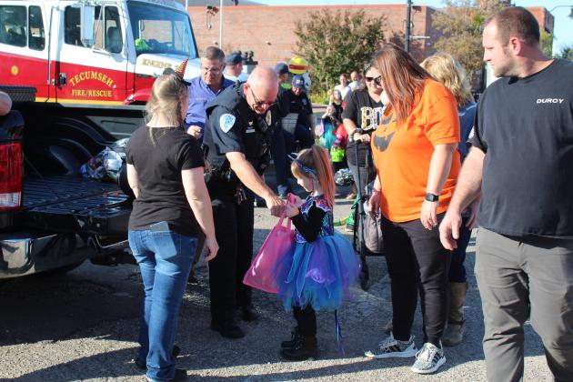 Tecumseh School Resource Officer J.D. Sanders hands out candy during the Tecumseh Business Trick-or-Treat, as Tecumseh Police Department Office Manager Tawana Gracy, left, and Police Chief J.D. Kidney, second from left, look on, Oct. 31. Countywide &amp; Sun/Natasha Dunagan