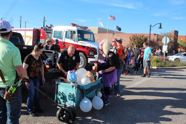 Tecumseh Police Department Office Manager Tawana Gracy and Tecumseh School Resource Officer J.D. Sanders hand out candy to Avery Salzer, 5, and Kaysen Salzer, 9 months, during the Tecumseh Business Trick-or-Treat, Oct. 31. Pushing their "bubble bath" is Emily Salzer, of Tecumseh. Countywide &amp; Sun/Natasha Dunagan