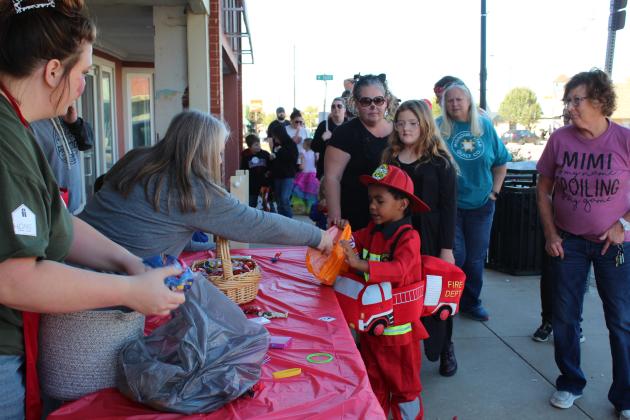Tatum Kuhn and Terri Williams, of New Ideas Printing, hand out candy to a little fireman during the Tecumseh Business Trick-or-Treat, Oct. 31. Countywide &amp; Sun/Natasha Dunagan