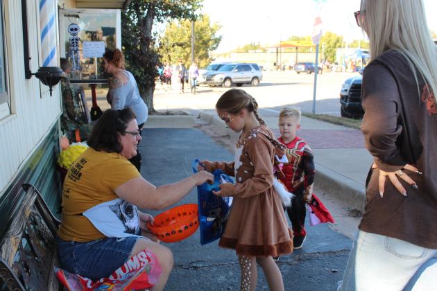 Fat Chix Barber owner Linda Blankenship adds to the bag of Paisley Jones, 8, of Tecumseh during Tecumseh Business Trick or Treat on Oct. 31. Blankenship said she had gone through 1,000 pieces of candy between 3:30-5 pm. Countywide &amp; Sun/Natasha Dunagan