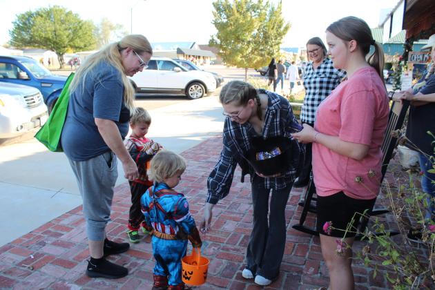Lanee Hogue and Karley Bills give candy to two little superheroes in front of The Farmer's Daughter Market, as owner Deann Smith looks on during Tecumseh Business Trick-or-Treat on Oct. 31. Countywide &amp; Sun/Natasha Dunagan