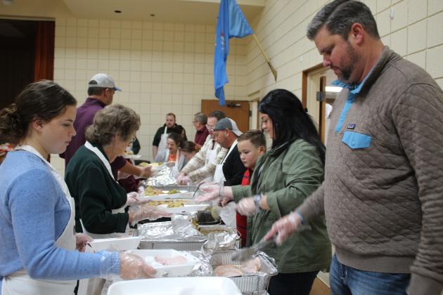 Katie Overstreet, far left, and Jordan Baker, far right, were among the many volunteers who worked to fill to-go boxes and serve the dine-in crowd during the 17th Annual Tecumseh Family Thanksgiving Dinner, held at the Tecumseh City Hall Auditorium on Nov. 24. About 997 people were fed during the event. Countywide &amp; Sun/Natasha Dunagan