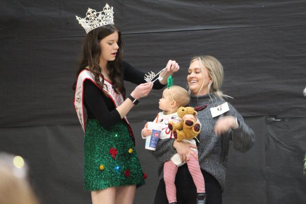 National Our Diamond Miss Queen Ashlynn Brady crowns Quinnley Fleming, of Asher, in the 13-24-month girls division of the Christmas Miss &amp; Mister Pageant on Dec. 3. She won Most Beautiful, Photogenic and Christmas Fashion Queen in her division. She is held by her mother, who is a teacher in Shawnee. Countywide &amp; Sun/Natasha Dunagan