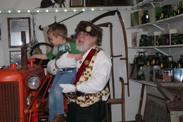 Santa holds Bryson Osborn, 3, of Konawa, up to see an Allis-Chalmers tractor at the Paul and Ann Milburn Center on Dec. 3. Santa will return to the Pottawatomie County history museum on Dec. 10, 1-4 pm. There will be no admission that day. An indoor light show can also be seen before Dec. 24. Countywide &amp; Sun/Natasha Dunagan
