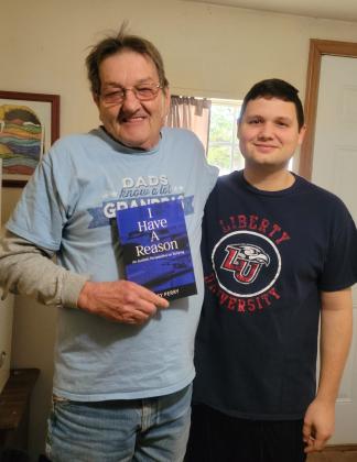 Author Joey Perry, right, presents his grandfather, Lloyd Perry, with a proof copy of his memoir, “I Have a Reason: An Autistic Perspective on Bullying.” Perry will have a book launch and signing Dec. 2, 6-7 pm, at The Farmers Daughter Market. Photo provided.