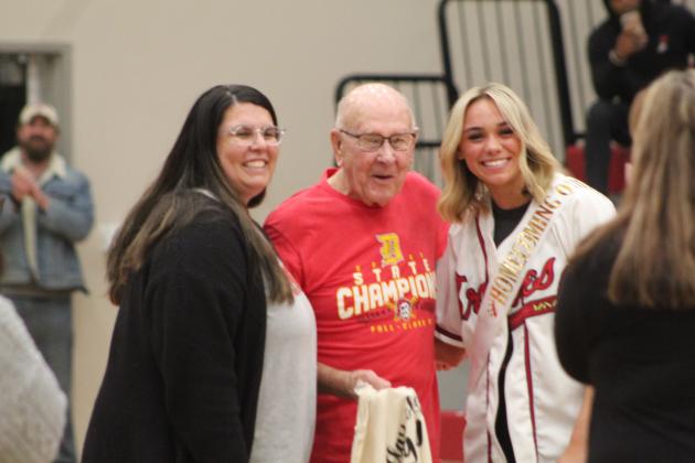 Dale teacher Ashley Barbosa, left, and Homecoming Queen Chayse Caram present a T-shirt to Dale 1949 Grad Harold Clark during the Lady Pirates homecoming game on Jan. 13. Countywide &amp; Sun/Natasha Dunagan