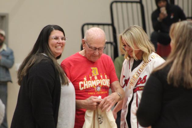 Dale teacher Ashley Barbosa, left, and Homecoming Queen Chayse Caram present a T-shirt to Dale 1949 Grad Harold Clark during the Lady Pirates homecoming game on Jan. 13. Countywide &amp; Sun/Natasha Dunagan