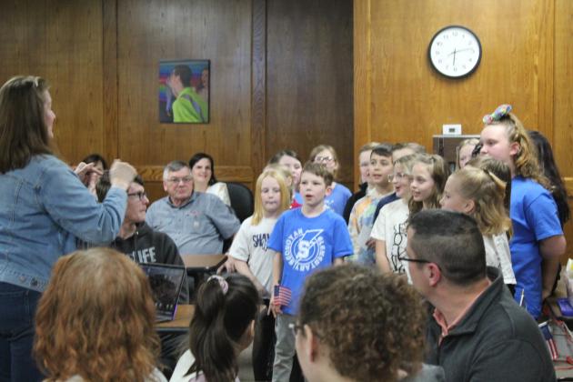 Jana Stelzer leads Sequoyah third-graders in "You're a Grand Old Flag."