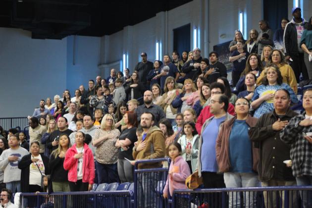The audience at the homecoming Shawnee basketball games participates in the flag salute on Jan. 10.