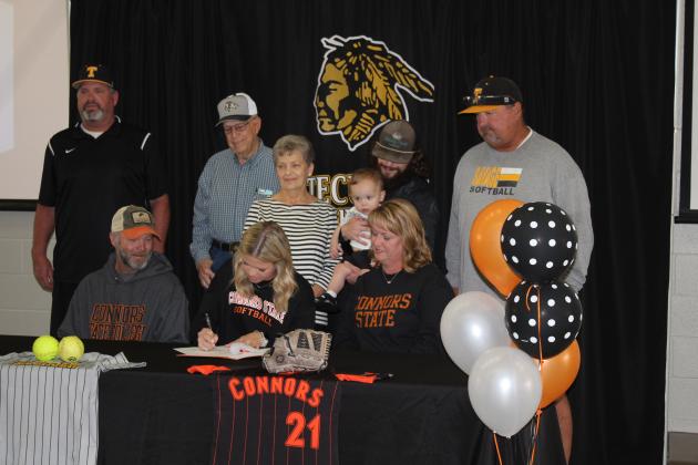 Tecumseh senior Katelyn Fleming signs a letter of intent to play softball at Connor's State College on April 3, as her family and coaches look on. Shown, front row from left, are father Shawn Fleming, Fleming, mother Shelley Fleming, back row, Coach Chad Trahan, grandfather Dave Fleming, grandmother Judy Fleming, brother Kyle Fleming with nephew Kayce Fleming, and Coach Perry Wilson. Countywide &amp; Sun/Natasha Dunagan