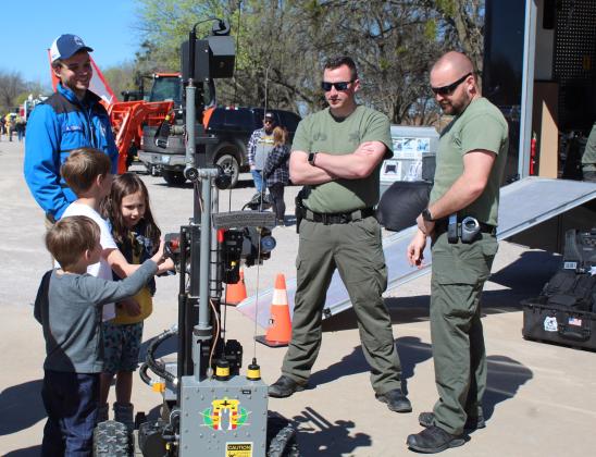 Milo, Julian, and Adelaide Edmison, of Shawnee, get hands-on experience with a bomb-detonating robot, as Deputy Matt Wagner and Sgt. David DeFord tell them about it. The Oklahoma County Sheriff's Bomb Squad robot was a popular attraction during the Touch-A-Truck and Beyond event at the CPN Festival Grounds on April 1. Countywide &amp; Sun/Natasha Dunagan