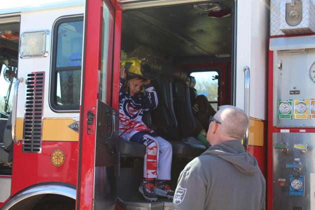 Chris Brady, 6, of Shawnee, tries on a firefighter's helmet while sitting in a Tecumseh Fire Department engine, as David Brown talks with him, during the Touch-A-Truck and Beyond event at the CPN Festival Grounds on April 1. Countywide &amp; Sun/Natasha Dunagan
