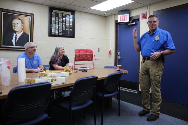 Tecumseh Police Chief J.R. Kidney speaks during the Tecumseh Chamber of Commerce monthly TAG meeting, May 11, as Anthony LaGrange and Kimberly Elliott listen. Behind them is a painting of fallen Police Chief Grover Butler, painted by retired detective Charles Spillers. Countywide &amp; Sun/Natasha Dunagan