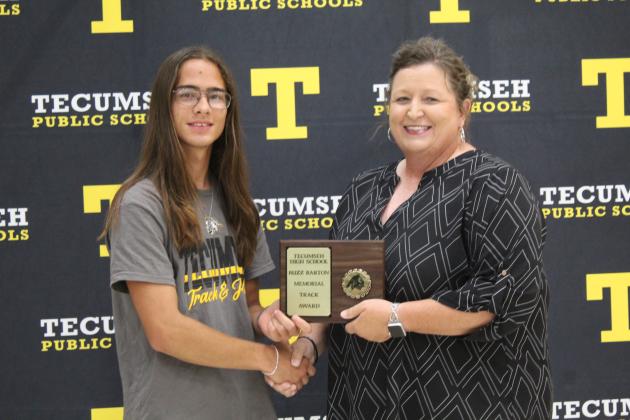 Track and Cross Country Coach Kortney Ozment presents the Buzz Barton Memorial Scholar/Athlete Award to James Negahnquet.
