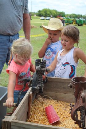 Lula Dailey, 2, turns a crank on a hand corn sheller owned by Mike Rooker of Dale, as Eli Dailey, 5, and Leila Dailey, 3, all of Earlsboro, watch during the Farming Heritage Festival at Shawnee Feed on June 17. Hosted by the Shawnee Tractor and Engine Club, the event is in its 24th year and also included several farming demonstrations, tractor pulling and an antique tractor parade on June 16 and 17. Countywide &amp; Sun/Natasha Dunagan