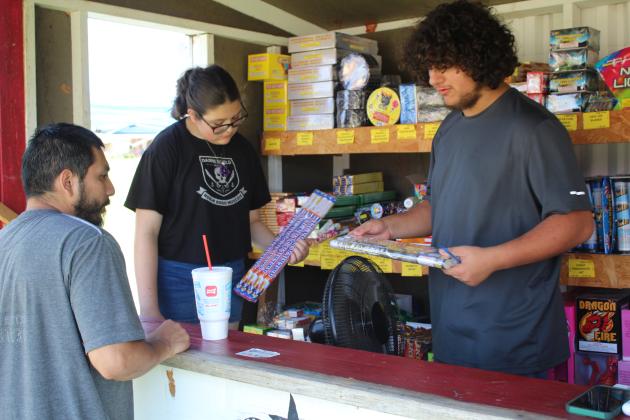 Tecumseh freshman Camryn Medley and junior Raistlin Stout assist Flavil Sosa of Shawnee in selecting fireworks at Tecumseh High School Band's fireworks stand on June 24. Band Director John Outon said they are raising money for a small band trip this year and their big Washington, DC and New York City trip in three years. This is the fourth year for them to sell fireworks, and the stand is open by Thunderbird Casino on Gordon Cooper Drive through July 5 every day, 9 am-10 pm, &amp; 9 am-11 pm, starting June 30.