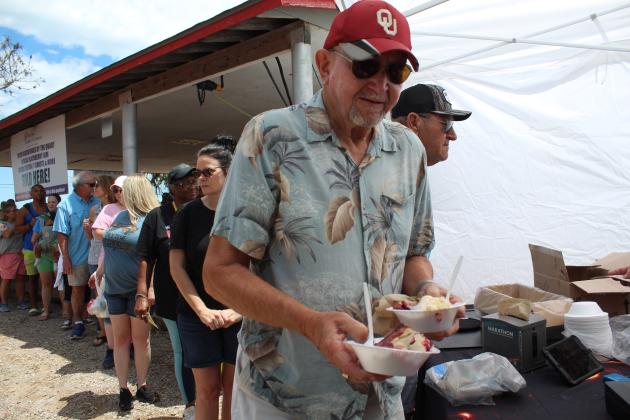 A.E. Murray, of OKC, buys blackberry cobbler from the Barbells &amp; BBQ booth at the McLoud Blackberry Festival on July 8, as a long line waits. Each food vendor was required to offer at least one blackberry item. Countywide &amp; Sun/Natasha Dunagan