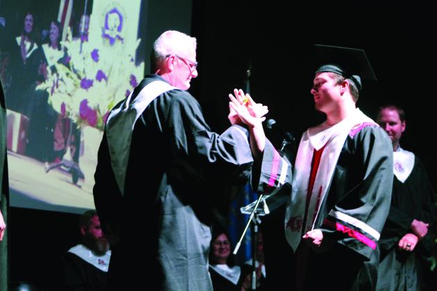 North Rock Creek High School Principal Chad Brooking shares a secret handshake with his son Holden Brooking after the graduate received his diploma at graduation on May 19. Countywide &amp; Sun/Natasha Dunagan