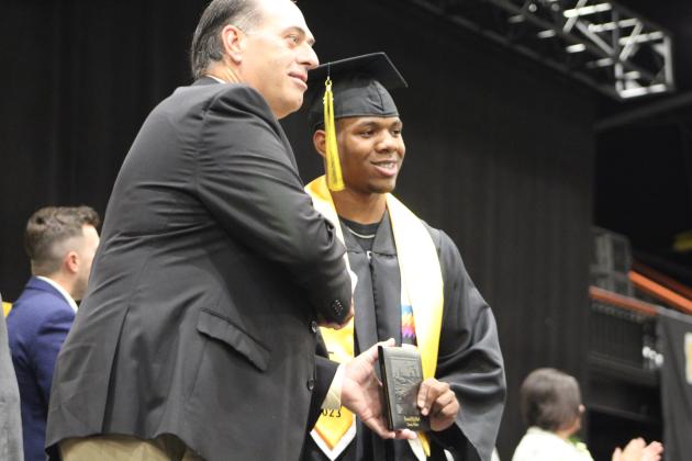 Tecumseh graduate Amos Galloway receives his diploma from Board President Todd Kennedy.