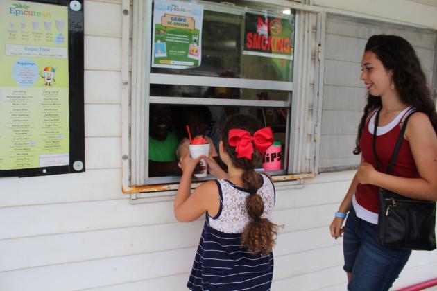 Tarryn Henry hands a snow cone to Sarah Jett, 8, as Raquel Jett, 18, waits.