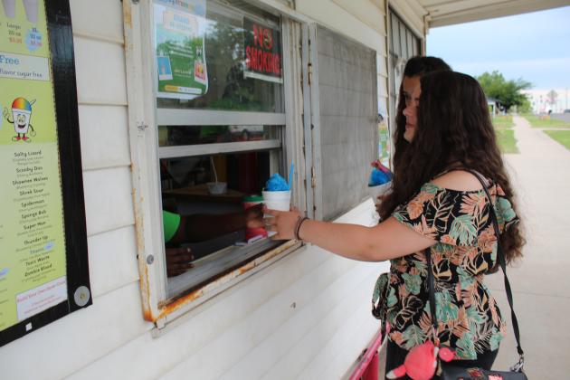 Esther Jett, 14, receives her snow cone from Tarryn Henry at Epic Sno Cones on July 3.