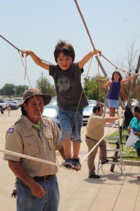Bill Williams, with Scout Troop 416, helps Samuel Castro, 4, of Moore, to cross a rope bridge at Cops N' Kids on Aug. 26. Also shown is Castro's sister, Nadalyn Castro, 7. Countywide &amp; Sun/Natasha Dunagan