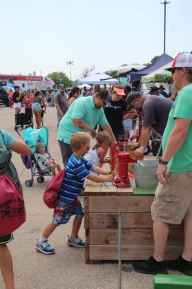 Isabella Baker, 4, of Tecumseh, is helped by her father, Brandon Baker, as she shells corn, and Robert Vaughn, of the Shawnee Tractor Club, far right, looks on as Austin Dibrell, 5, of Midwest City, pumps water at Cops N' Kids, Aug. 26. This was the first year for the club to participate. Countywide &amp; Sun/Natasha Dunagan
