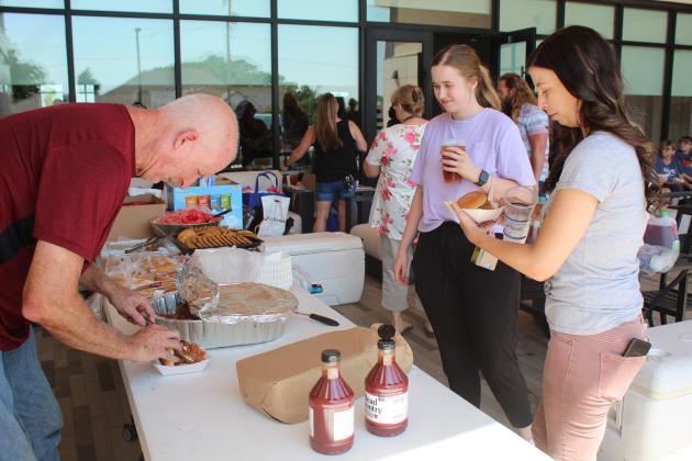 Volunteer Jeff Sigman serves barbecue sandwiches for Cross Timbers Elementary fourth-grade teachers Katie Logsdon and Anna Irvine. Sigman said he smoked enough meat for 250 sandwiches. The teachers' lunch, during the Second Annual Pack the School Teacher Supply Stop, was sponsored by First United Bank, Community Renewal and H Tea O on Aug. 1. Countywide &amp; Sun/Natasha Dunagan