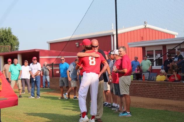 1979 State Champion team member John (Tony) Plunkett receives a hug and a game ball from his nephew, senior Cade Dickinson.