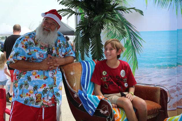 Santa Claus poses with Thatcher Guess, 11, of Prague, during Cops N' Kids, held at the Heart of Oklahoma Expo Center on Aug. 26. Santa and Mrs. Claus dressed for the heat this year, with a tropical "Santa on Vacation" theme. Countywide &amp; Sun/Natasha Dunagan