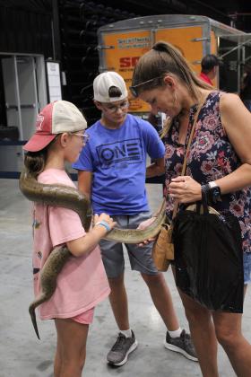 A Burmese Python held by Maryn Brown, 9, of Wynnewood makes friends with Brown's mom, Ashley, as Outdoor Nation Expo volunteer Mason Eversole, 13, waits to take the snake back on Aug. 12. The python was part of the Extreme Animals attraction. Countywide &amp; Sun/Natasha Dunagan