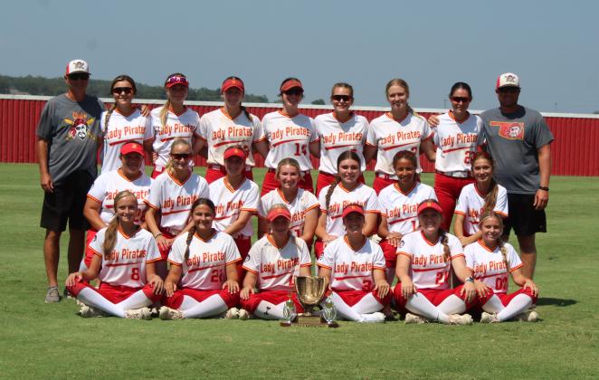 The Dale Lady Pirates and their coaches Andy Powell and Bryce Clemons pose with their Champion trophy after winning the Dale-Tecumseh Tournament on Sept. 9. Over the three-day tourny, they took all five of their games, including the last game with Runners-Up Purcell.