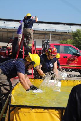 Cale Eberle and Michelle Dusing, on the Asher team, compete in the bucket brigade of the Firefighter Olympics on Sept. 9. Travis Wells is on the ladder filling a barrel. The Firefighter Olympics is a long-standing tradition at the Pott. County Free Fair. Countywide &amp; Sun/Natasha Dunagan