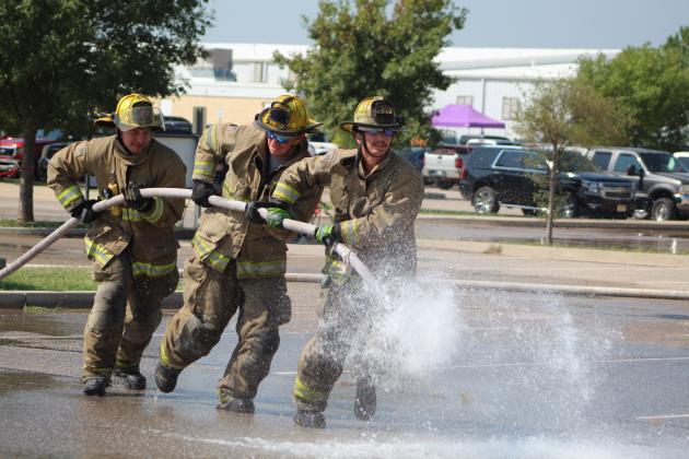 Tecumseh firefighters Dylan Taylor, Langston Ray and Lane Cooper compete in the Firefighter Olympics at the Pott. County Free Fair on Sept. 9. They were carrying the hose to Justin Hamby who was up a ladder waiting to fill a barrel. Countywide &amp; Sun/Natasha Dunagan