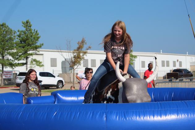 Seanna Ford of Meeker tries riding a mechanical bull as Serenity Nevel and Donna Snead look on at the Pottawatomie County Free Fair on Sept. 9. Countywide &amp; Sun/Natasha Dunagan