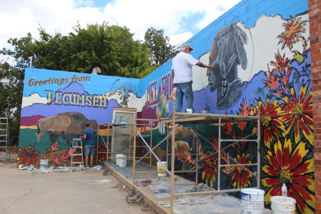 Bob Palmer, foreground, and Shane Cox work on a mural, Oct. 11, on the west side of the building at 421 E. Walnut in Tecumseh. The former laundromat next to Ma Beasley's Daylight Donuts is owned by Joshua and Katie Goodson, and will soon open as Affinity Corporation, a construction and design business. Katie Goodson said she wanted bright colors and Tecumseh and Oklahoma images, and she is happy with the result, which took two days to complete.