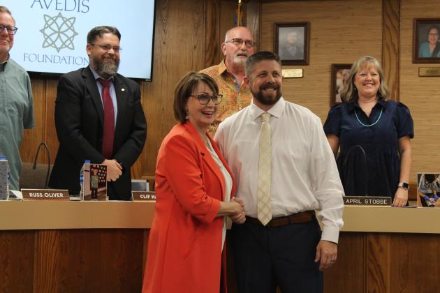 Dr. Kathy Laster, CEO of the Avedis Foundation, shakes hands with Dr. Aaron Espolt, Shawnee Public Schools superintendent, in recognition of Avedis donating $500,000 for tornado recovery. Standing behind them are members of the Shawnee Board of Education, during their Nov. 6 meeting. Countywide &amp; Sun/Natasha Dunagan