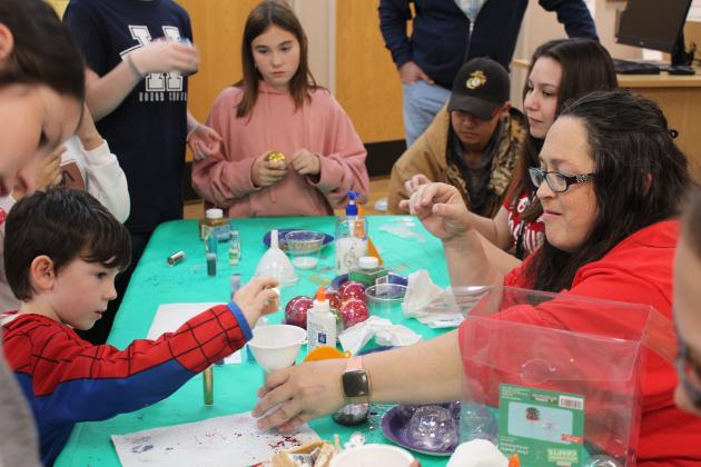 Shawnee Pioneer Library employee Cecilia Young, far right, helps Brayton Schwertner, 5, of Midwest City, to add glitter to the inside of a clear ornament during the Shawnee Tree Lighting event on Nov. 17. Kids could also visit with Santa Claus, make gingerbread houses, and create something in the Maker Lab. Countywide &amp; Sun/Natasha Dunagan