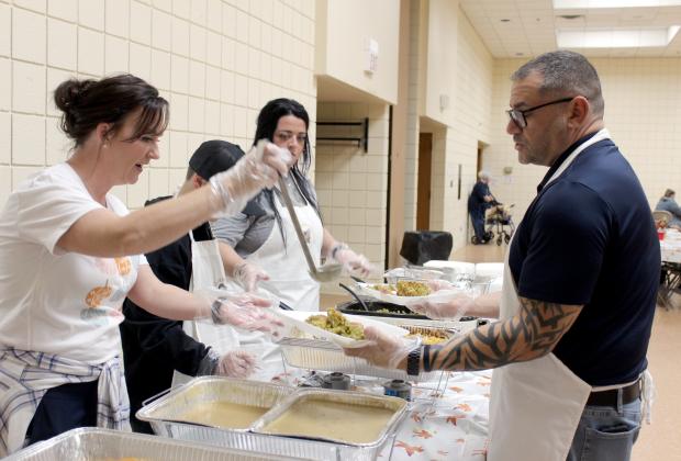 Dustie Baker, far left, adds gravy to two meals held by OKC Police Sergeant John Blumenthal during the 18th Annual Tecumseh Family Thanksgiving Dinner at Tecumseh City Hall Auditorium on Nov. 23. Blumenthal is friends with Tecumseh Police Chief J.R. Kidney, and he and his mother decided to work the dinner this year, along with OKCPD Chaplain Terry Woodward, who played saxophone for the event. Countywide &amp; Sun/Natasha Dunagan