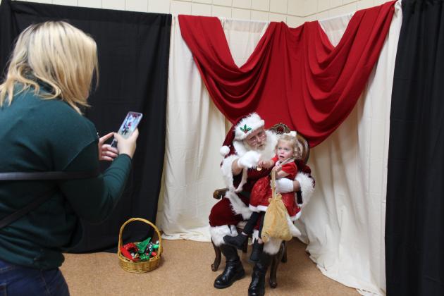 Alexis Martin takes a picture of Ali Cox, 2, of Tecumseh, on Santa's lap at the Grinchmas Whoville event on Nov. 30.