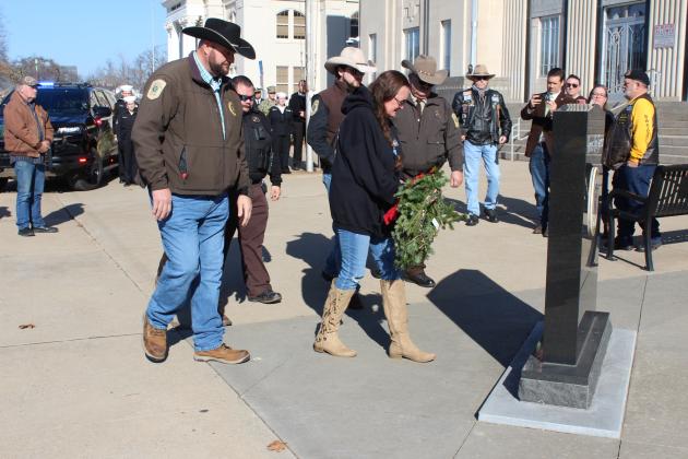With the support of several Pottawatomie County Sheriff's deputies and other law enforcement officers, Terri Condit places a wreath on the Fallen Officers memorial in front of the Pott. Co. Courthouse on Dec. 16. Condit is the mother of the late Jarate Condit, who was an Asher police officer, and she was observing National Wreaths Across America Day. Countywide &amp; Sun/Natasha Dunagan