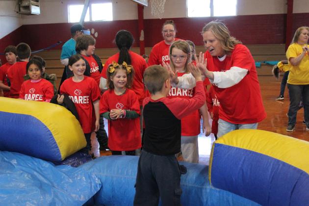 Earlsboro first-grade teacher Lisa Coomer gives Kaden Spurlin high-fives as he joins the "Roaree" family. About 90 first- through fifth-graders participated in the positive behavior intervention "sorting ceremony," where they spun a wheel to choose one of four families, slid down an inflatable slide and got a T-shirt on Jan. 17. Each week, the family with the most points for good behavior will receive a reward. Countywide &amp; Sun/Natasha Dunagan