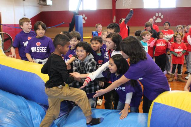 Earlsboro Elementary student Gunner Sullivan gets high-fives from his fellow "Wassee family" members. About 90 first- through fifth-graders participated in the positive behavior intervention "sorting ceremony," where they spun a wheel to choose one of four families, slid down an inflatable slide and got a T-shirt on Jan. 17. Each week, the family with the most points for good behavior will receive a reward. Countywide &amp; Sun/Natasha Dunagan