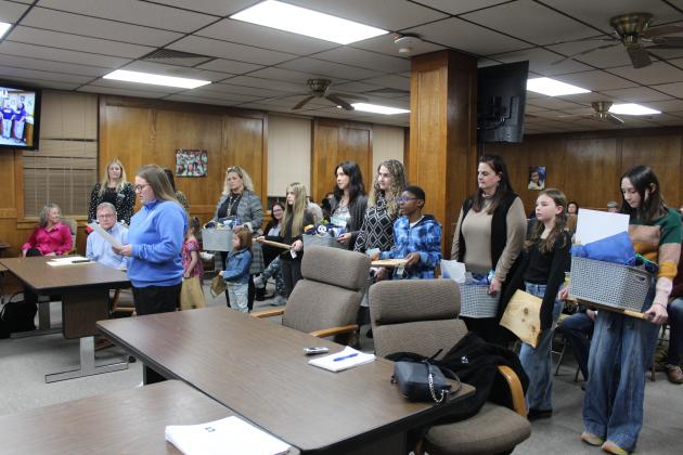 SHS FFA Advisor Jordan Miller reads a speech by Shawnee FFA President Hope Sitton, as administrators and students wait to present gifts to the school board.