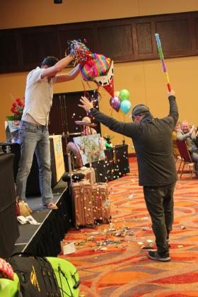 Brandon Montgomery was the first to take a crack at one of three piñatas during the Tecumseh "Cha-Cha" Chamber Auction, held at the Grand Casino Hotel &amp; Resort on Feb. 8. Also shown is Luke Fugate, left, shaking out the pinata which contained money. Countywide &amp; Sun/Natasha Dunagan