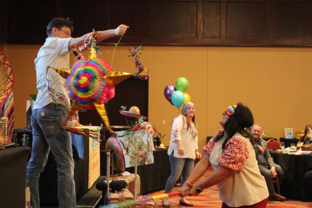 Twana Griffith swings at a piñata held by Luke Fugate, as Tecumseh Chamber of Commerce Executive Director Kimberly Elliott watches during the Tecumseh "Cha-Cha" Chamber Auction, held at the Grand Casino Hotel &amp; Resort on Feb. 8. Her piñata contained jewelry. Countywide &amp; Sun/Natasha Dunagan