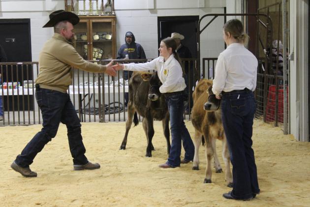 Tecumseh alum and Livestock Judge Dexter Matlock shakes hands with Mattie Taron, who showed in the Dairy Cattle division of the Tecumseh 4-H and FFA Local Livestock Show, Feb. 17, with her sister Addison Taron. Countywide &amp; Sun/Natasha Dunagan