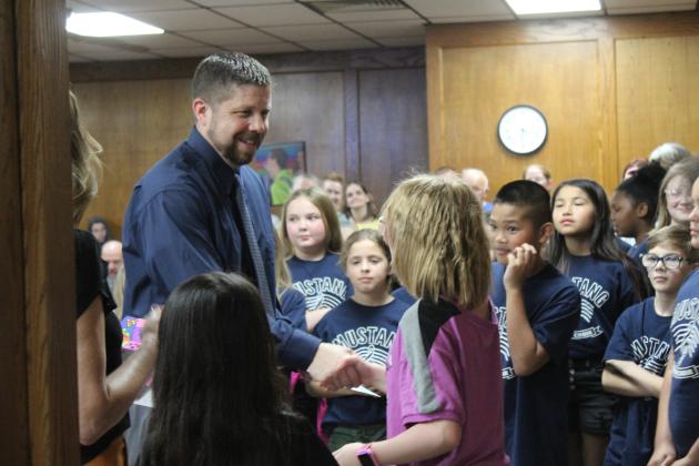 Horace Mann Elementary student Bella Manley presents her artwork to Shawnee Superintendent Dr. Aaron Espolt and gets a handshake during the March 4 SPS Board of Education meeting. Artwork was also given to the board members and other administrators. Countywide &amp; Sun/Natasha Dunagan