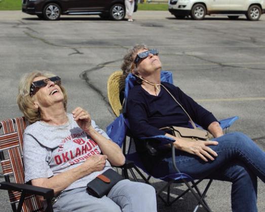 Shirley Parker and Carolyn McCraw, both of Tecumseh, watch as the moon’s shadow crosses the sun during the Tecumseh Public Library Eclipse Viewing Party, held at the Tecumseh Pentecostal Church of God parking lot on April 8. Countywide &amp; Sun/ Natasha Dunagan
